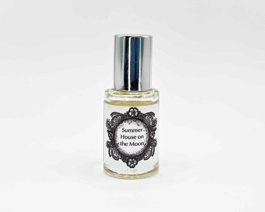 Summer House on the Moon Fragrance 5mL bottle. Cylindrical clear glass with Life on the Moon Collection artwork label and a cylindrical silver top.
