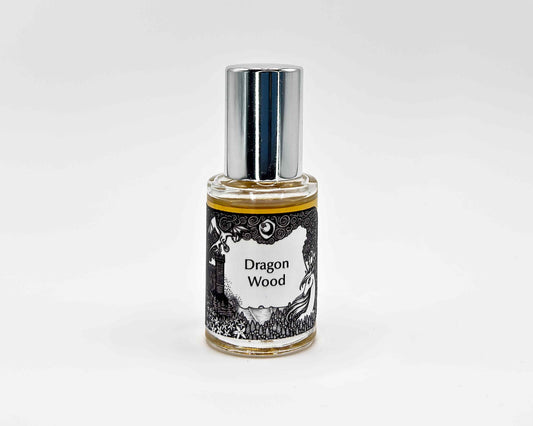 Dragon Wood Fragrance 5mL bottle. Cylindrical clear glass with Lost Fairytale Collection artwork label and a cylindrical silver top.