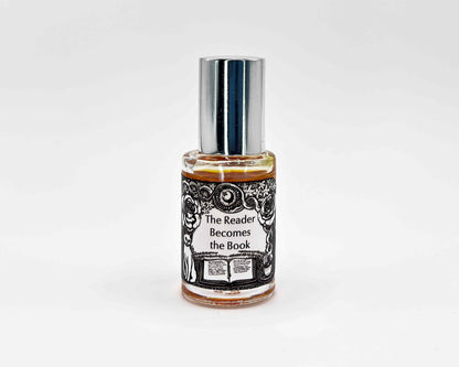The Reader Becomes the Book Fragrance 5mL bottle. Cylindrical clear glass with Gt Lit Collection artwork label and a cylindrical silver top.