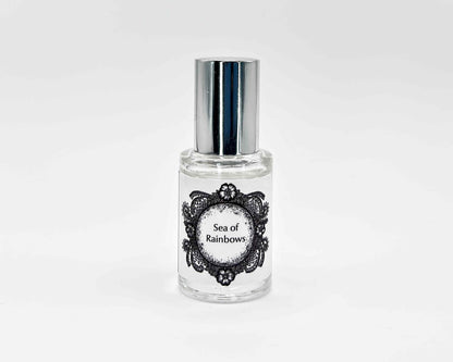 Sea of Rainbows Fragrance 5mL bottle. Cylindrical clear glass with Life on the Moon Collection artwork label and a cylindrical silver top.