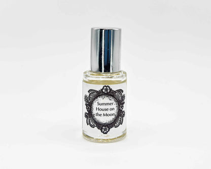 Summer House on the Moon Fragrance 5mL bottle. Cylindrical clear glass with Life on the Moon Collection artwork label and a cylindrical silver top.