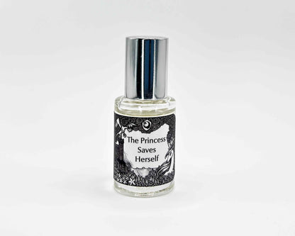 The Princess Saves Herself Fragrance 5mL bottle. Cylindrical clear glass with Lost Fairytale Collection artwork label and a cylindrical silver top.
