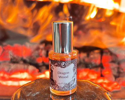 5 mL glass perfume bottle with silver top of the scent "Dragon Wood" in front of a roaring fire.