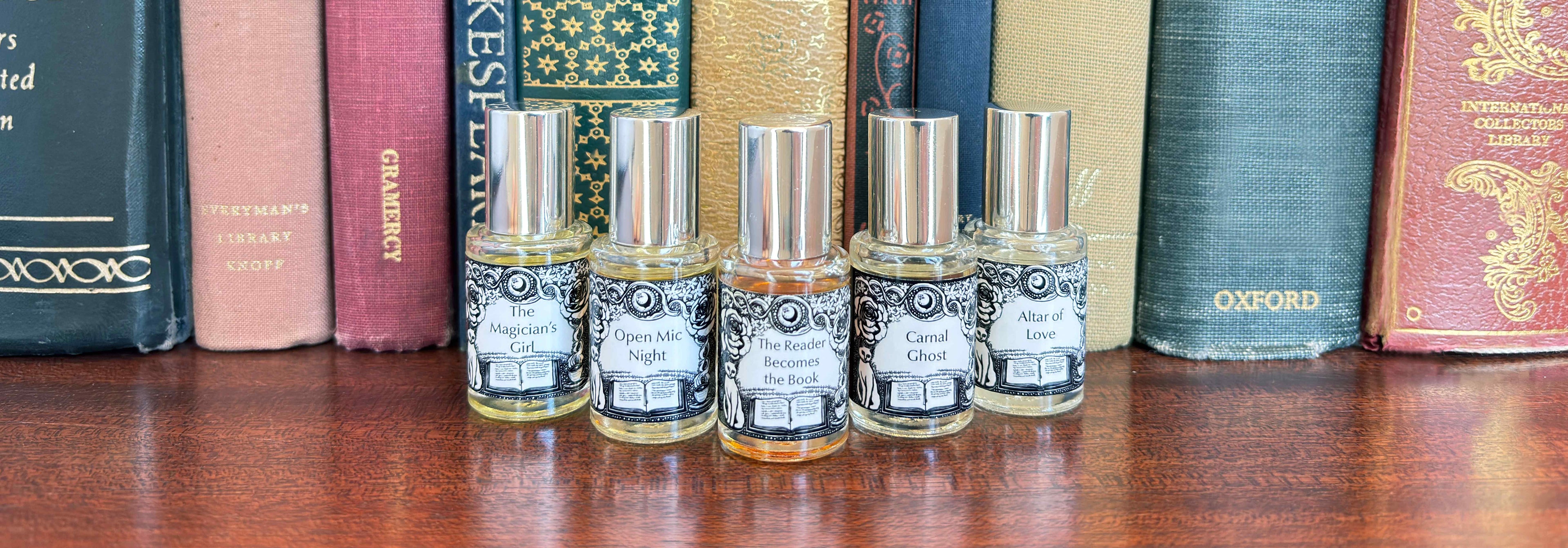 All five Get Lit Collection 5 mL bottles lined up on a wood surface in front of vintage books.