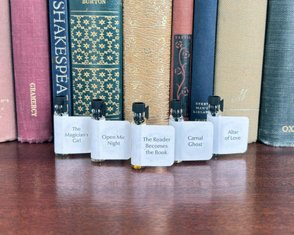 All five Get Lit Collection sample bottles lined up on a wood surface in front of vintage books.