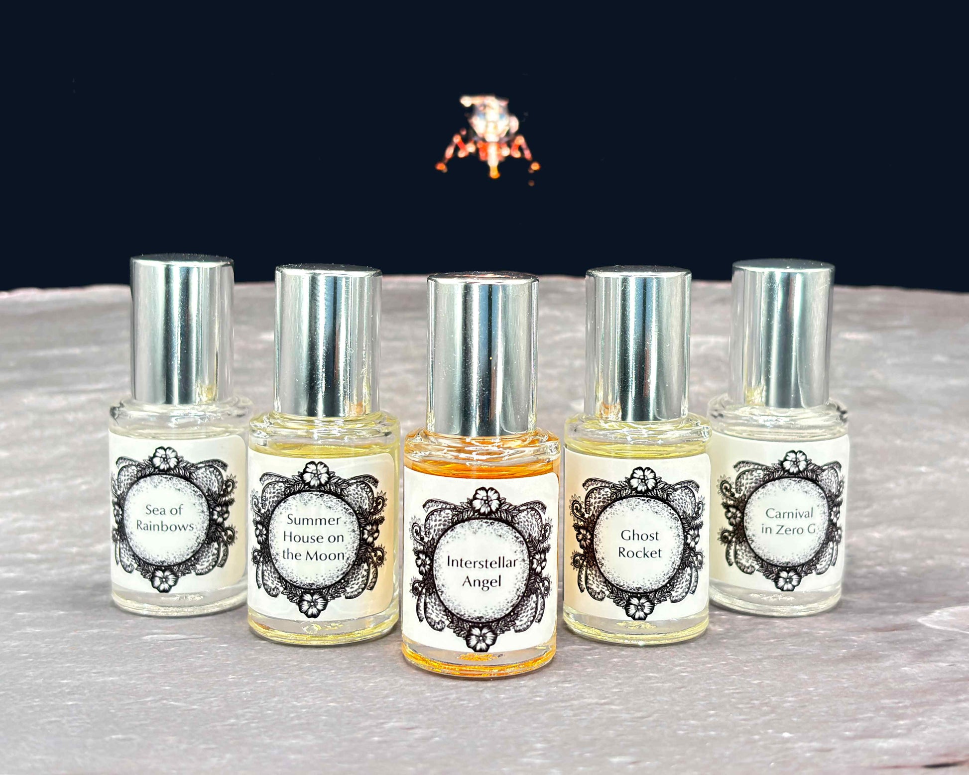 All five Life on the Moon Collection 5 mL bottles lined up on a moonscape with a lunar lander in the background.