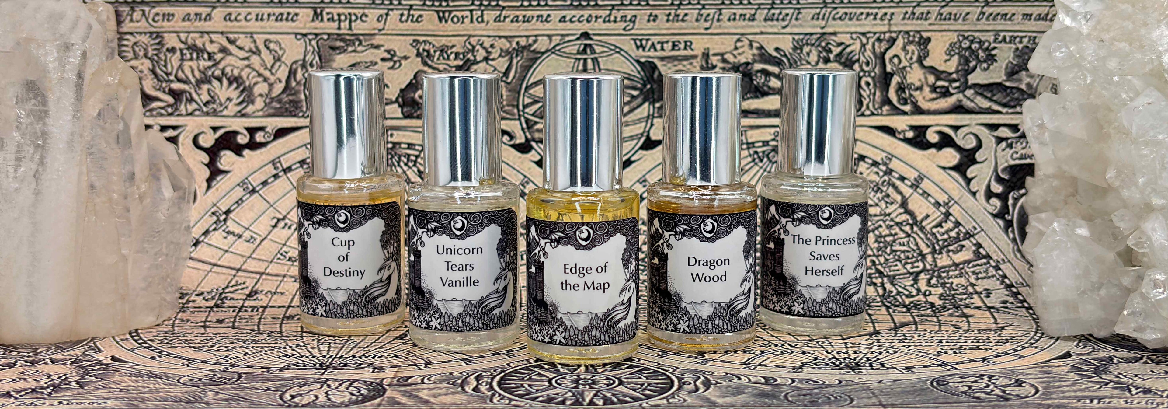 All five Lost Fairytale 5 mL bottles lined up on a vintage map between large white crystals.
