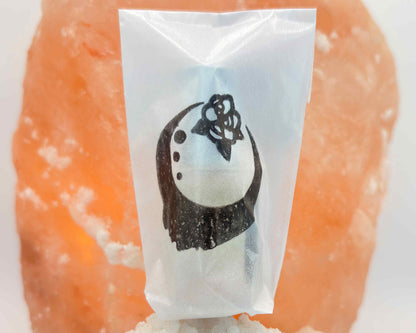 Close-up view of perfume bottle packaged in a glassine envelope, in front of a salt crystal.