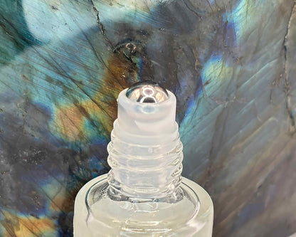Close-up view of perfume bottle roller top, in front of a labradorite crystal.