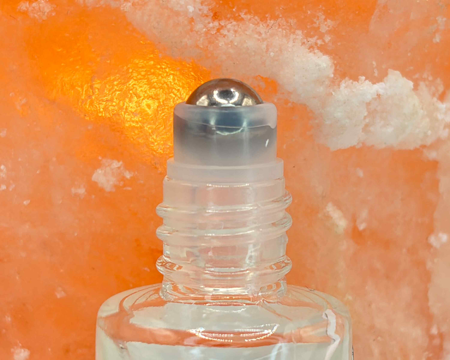 Close-up view of perfume bottle roller top, in front of a salt crystal.
