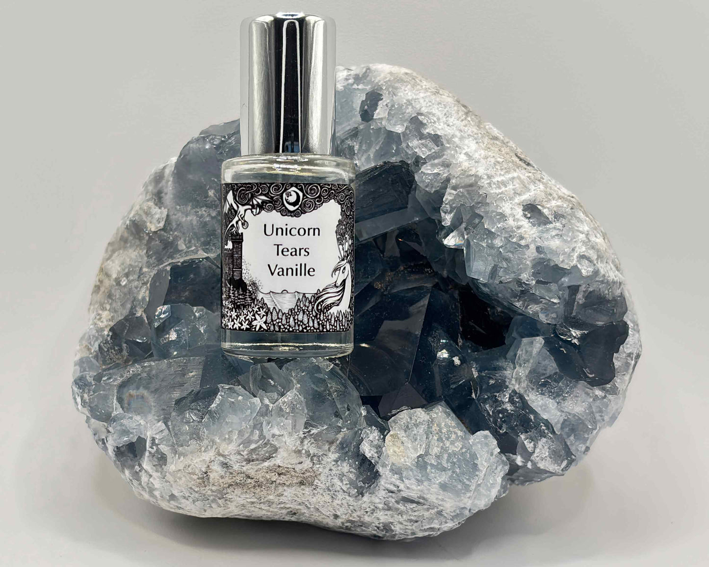 5 mL glass perfume bottle with silver cap of the scent "Unicorn Tears Vanille" nestled in a blue celestite crystal.