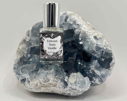 5 mL glass perfume bottle with silver cap of the scent "Unicorn Tears Vanille" nestled in a blue celestite crystal.